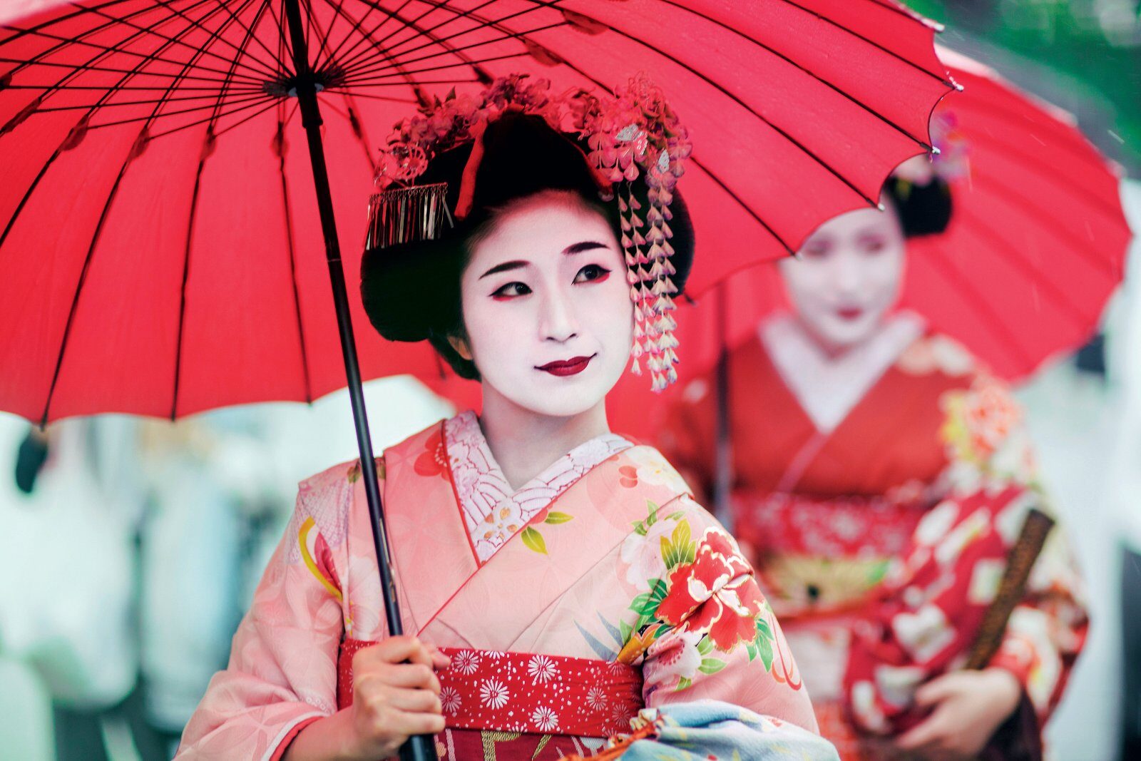 Geishas en kimono sous une ombrelle rouge, à Kyoto