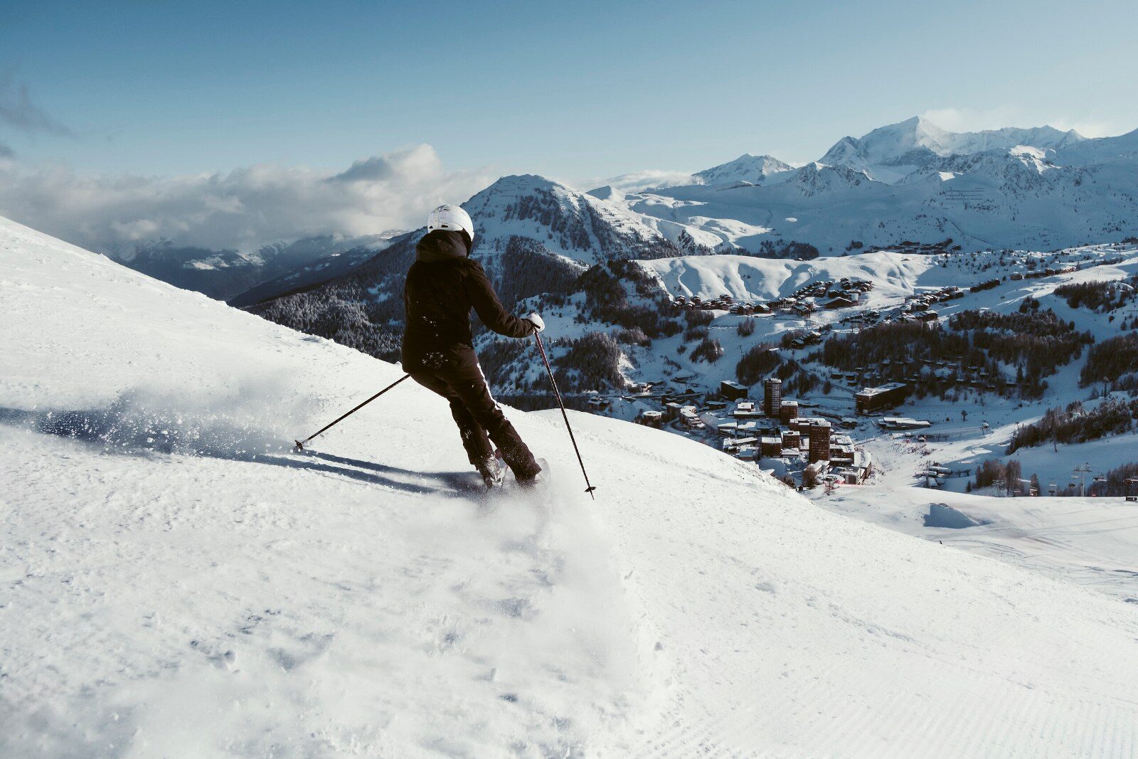 A skier on a slope facing the Alpine peaks A skier on a slope facing the Alpine peaks