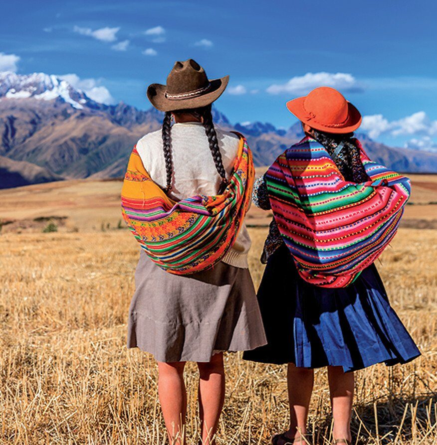 Andean women in traditional dress before the mountains