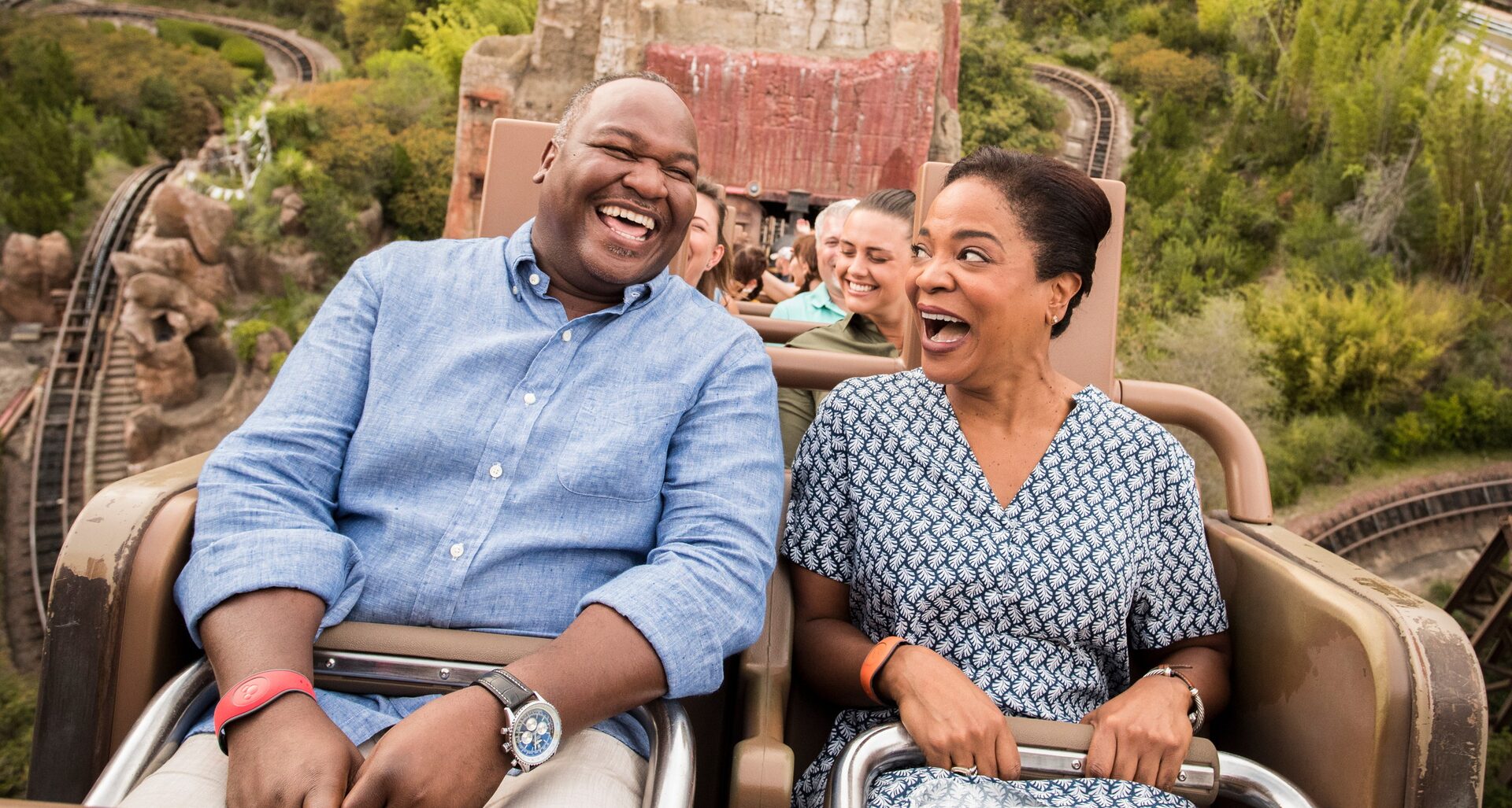 A couple laughs in the Expedition Everest ride car, the rocky mountain behind them, at Disney’s Animal Kingdom