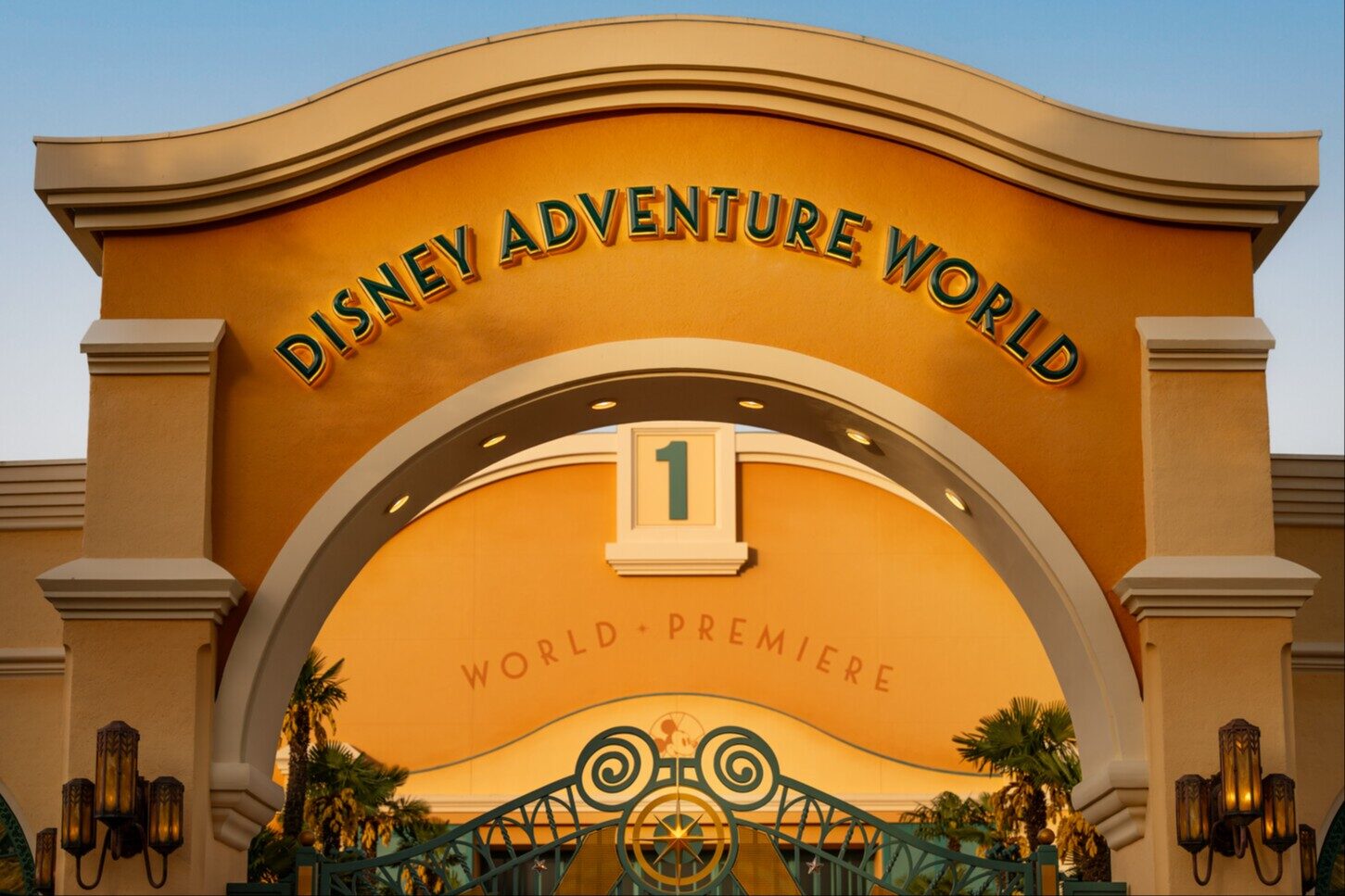 The entrance arch of Disney Adventure World, glowing in the sun, with the park name in raised lettering. Photo: ©Disney.