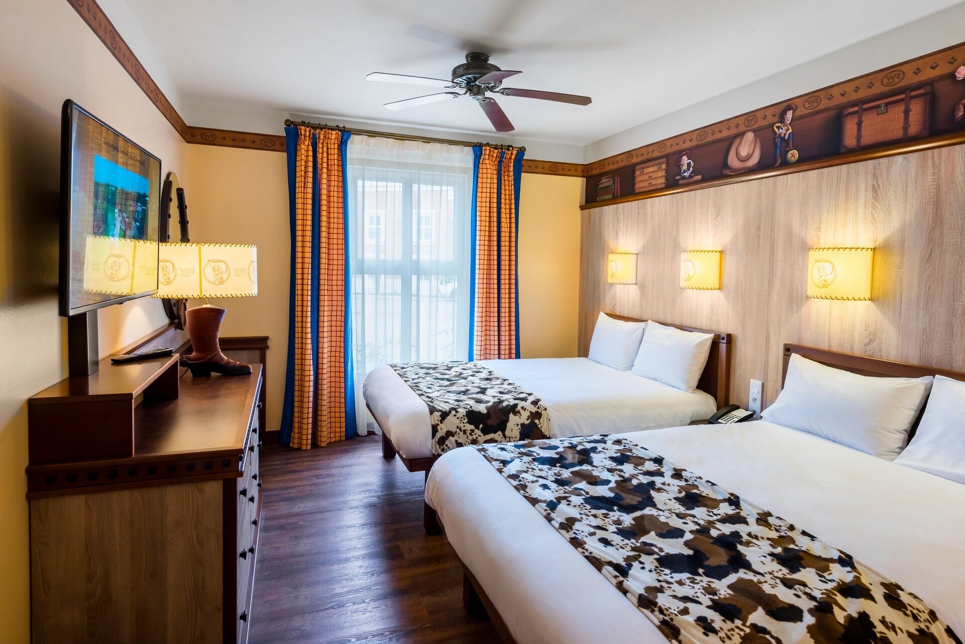 Une chambre du Disney Hotel Cheyenne, avec deux grands lits aux couvre-lits imprimés vache et un décor de ranch aux tons chauds. Photo : ©Disney/Pixar. Une chambre du Disney Hotel Cheyenne, avec deux grands lits aux couvre-lits imprimés vache et un décor de ranch aux tons chauds. Photo : ©Disney/Pixar.