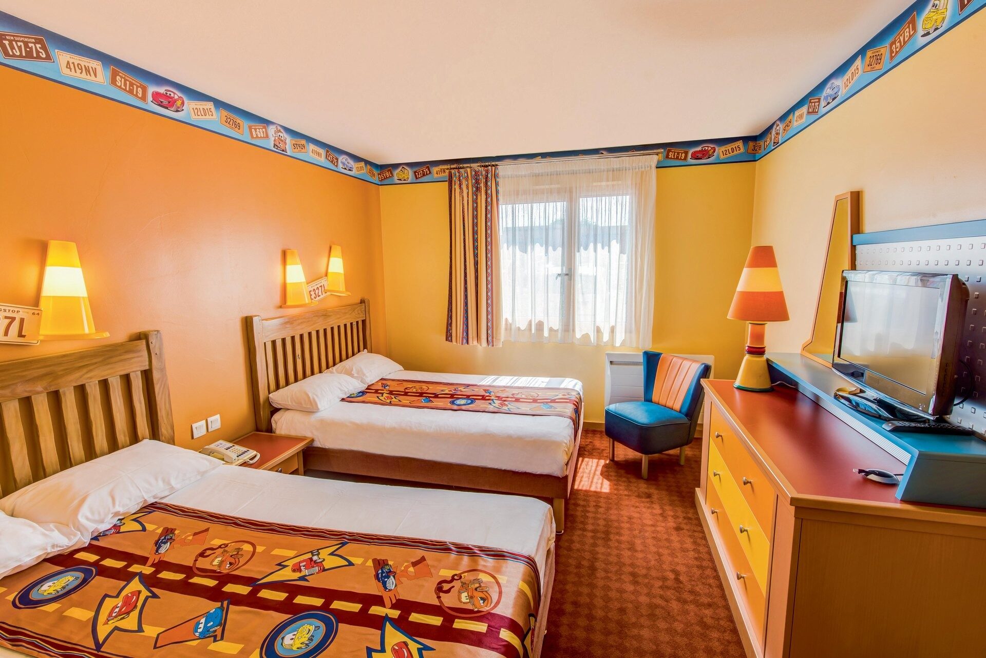 Une chambre du Disney Hotel Santa Fe, avec deux grands lits, des murs jaune soleil et une frise colorée inspirée de la route. Photo : ©Disney/Pixar. Une chambre du Disney Hotel Santa Fe, avec deux grands lits, des murs jaune soleil et une frise colorée inspirée de la route. Photo : ©Disney/Pixar.