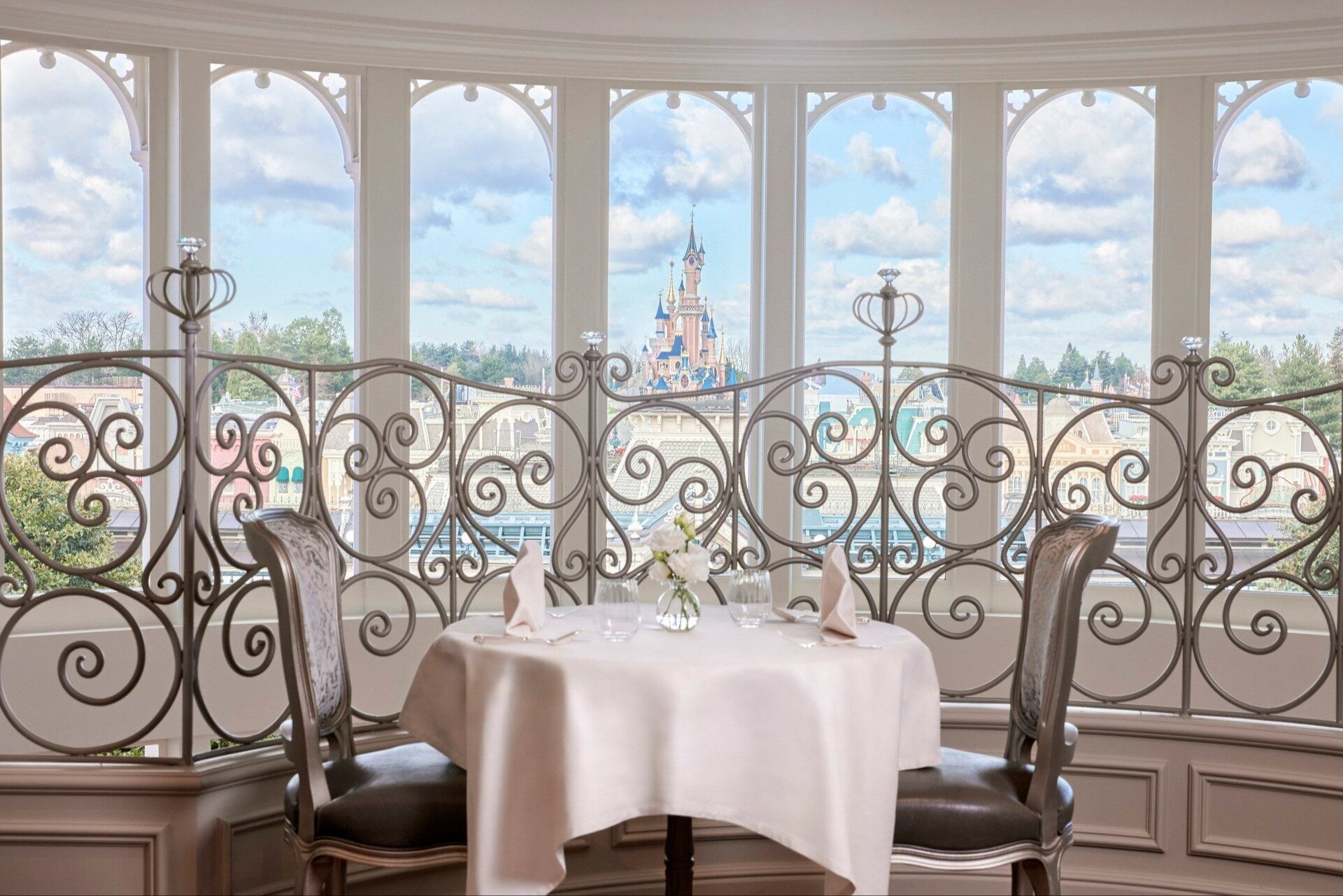 A table set at the Castle Club of Disneyland Hotel, behind a wrought-iron balustrade overlooking Sleeping Beauty Castle. Photo: ©Disney.