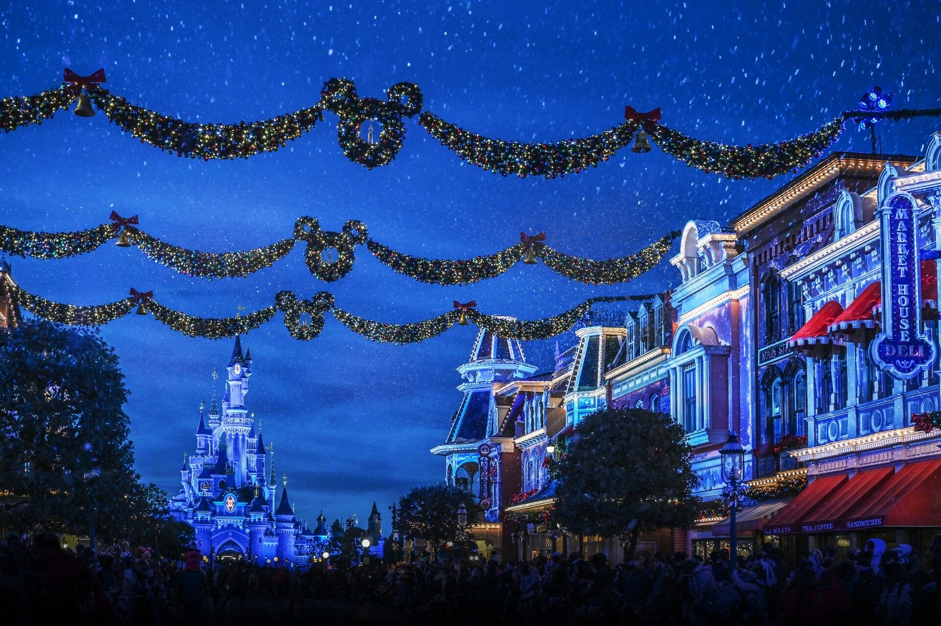 Main Street, U.S.A. hung with Christmas garlands on a winter evening, with the lit castle at the end of the street. Photo: ©Disney.