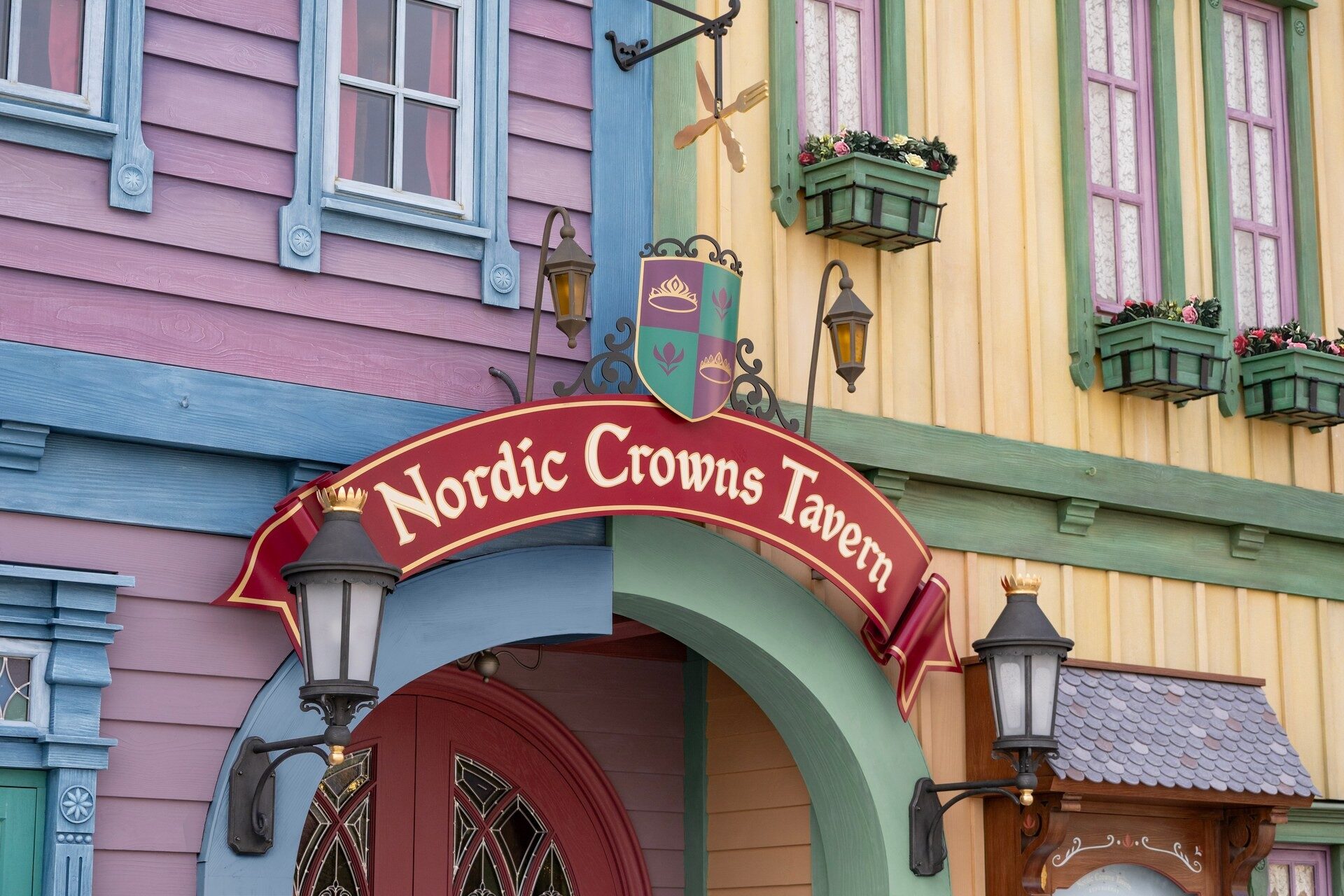 L'enseigne de la Nordic Crowns Tavern dans le village d'Arendelle, à World of Frozen, entre les façades colorées aux fenêtres fleuries. Photo : ©Disney. L'enseigne de la Nordic Crowns Tavern dans le village d'Arendelle, à World of Frozen, entre les façades colorées aux fenêtres fleuries. Photo : ©Disney.