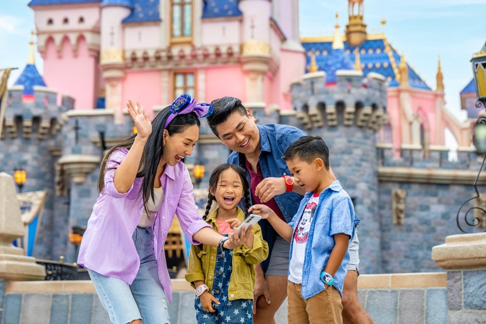 Une famille pose devant le château de la Belle au bois dormant, au parc Disneyland Une famille pose devant le château de la Belle au bois dormant, au parc Disneyland