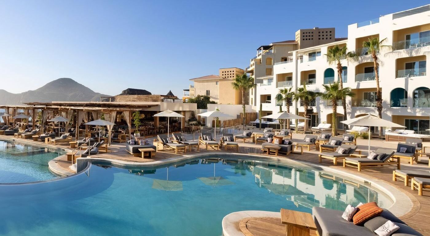 The pool at ME Cabo Adults Only by Meliá in Cabo San Lucas, Mexico, with loungers and mountains in the background The pool at ME Cabo Adults Only by Meliá in Cabo San Lucas, Mexico, with loungers and mountains in the background