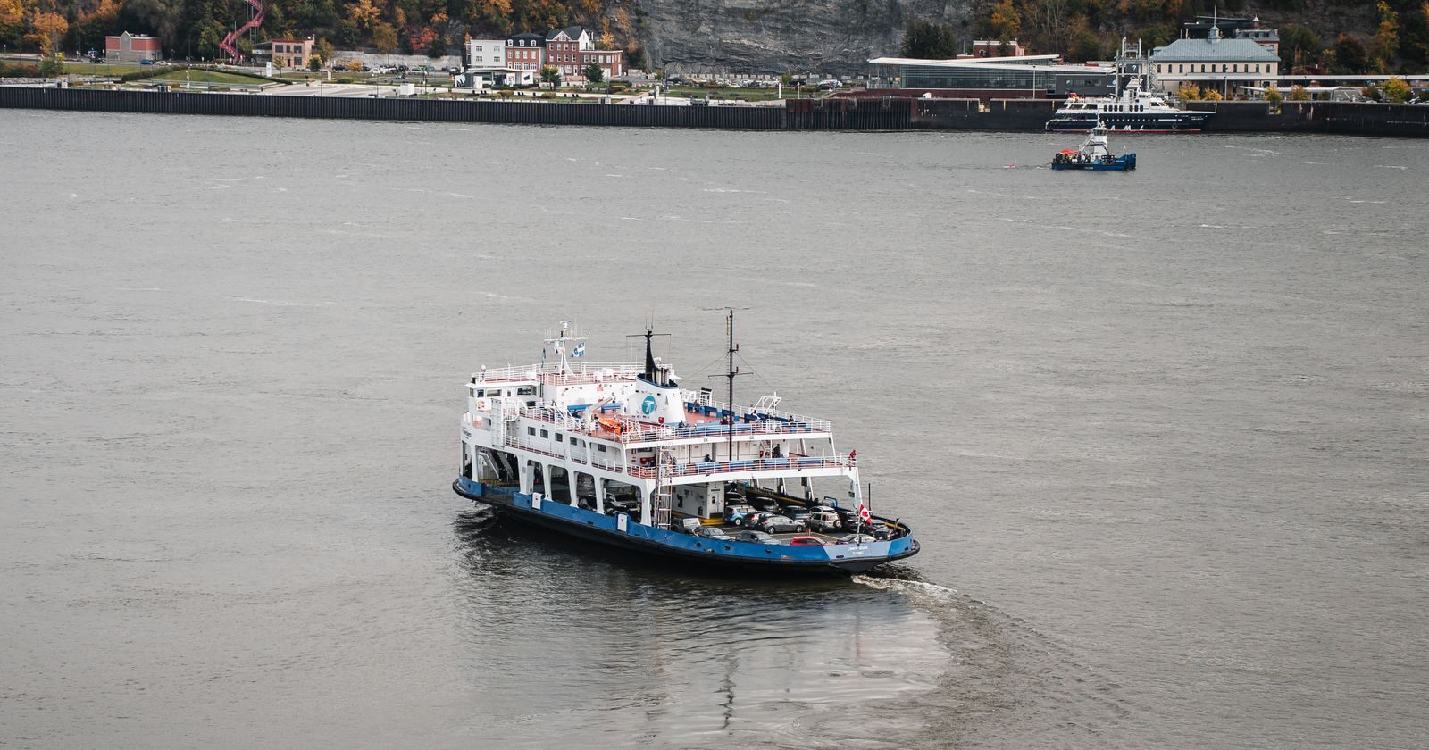 Ship sailing the St. Lawrence River past the wooded cliffs of Quebec City in autumn colours