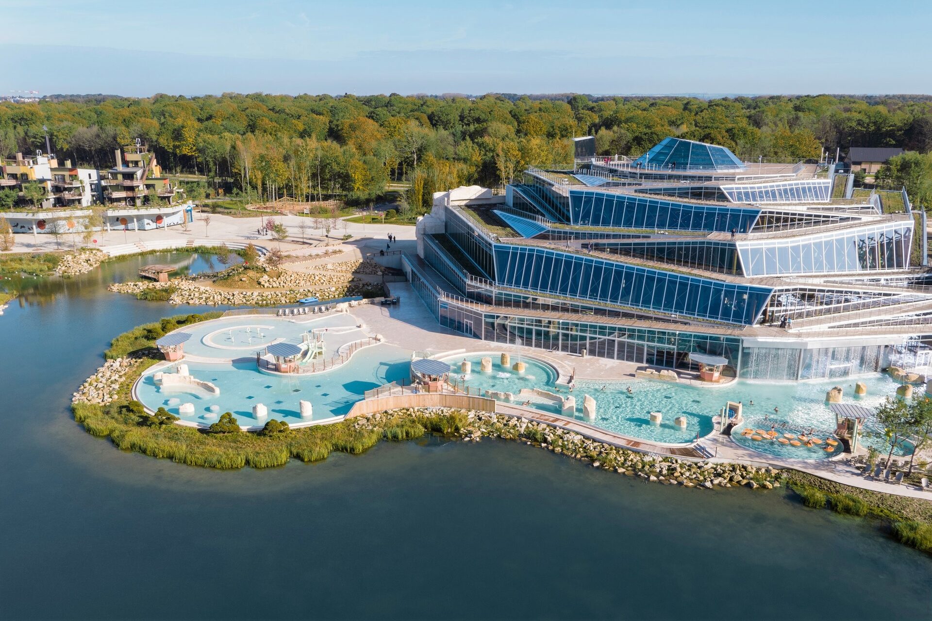 Vue aérienne de l'Aqualagon de Villages Nature Paris, avec ses bassins extérieurs au bord du lac. Photo : © Aeriallive. Vue aérienne de l'Aqualagon de Villages Nature Paris, avec ses bassins extérieurs au bord du lac. Photo : © Aeriallive.